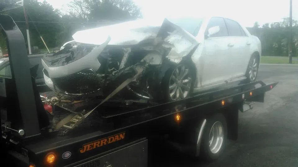A white car is sitting on top of a tow truck
