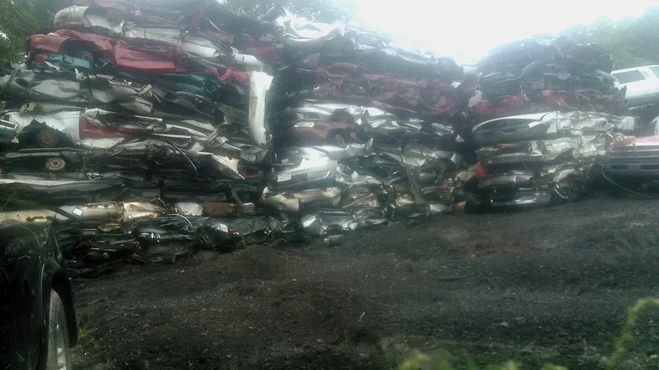 A pile of cars is sitting on top of each other on a dirt road