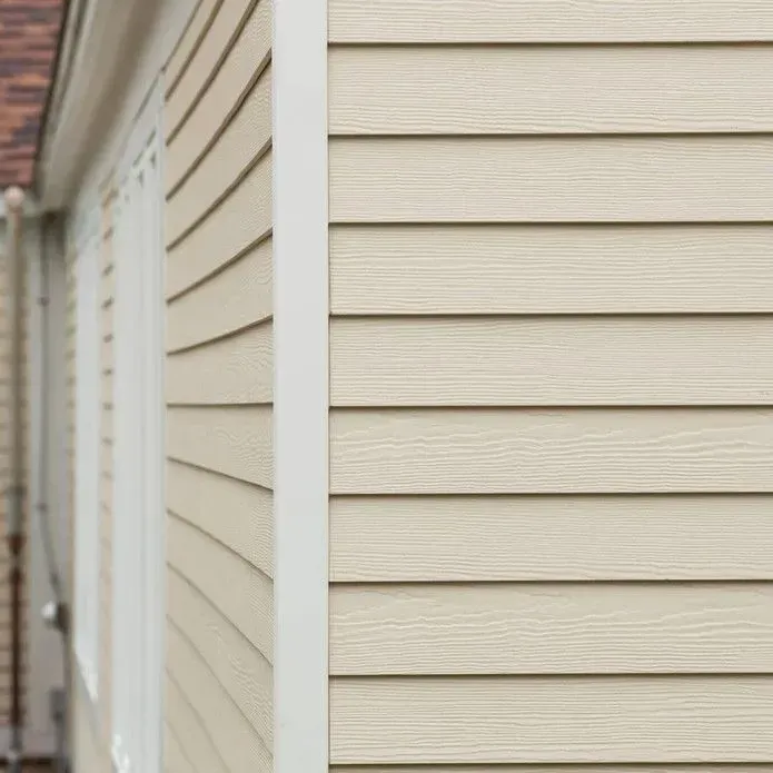 Exterior view of a corner of a building with light beige horizontal lap siding and white trim.