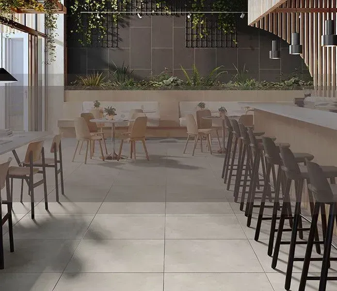 A modern restaurant patio with light-colored tile floors, wooden chairs, tables, and a bar area with high stools.