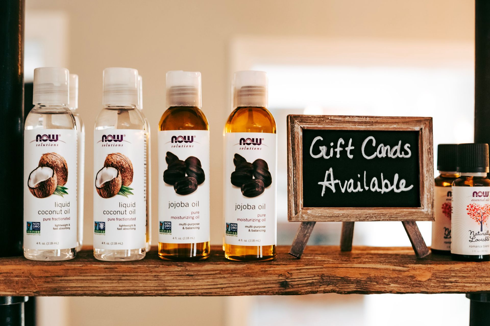 A shelf with bottles of oil and a sign that says gift cards available