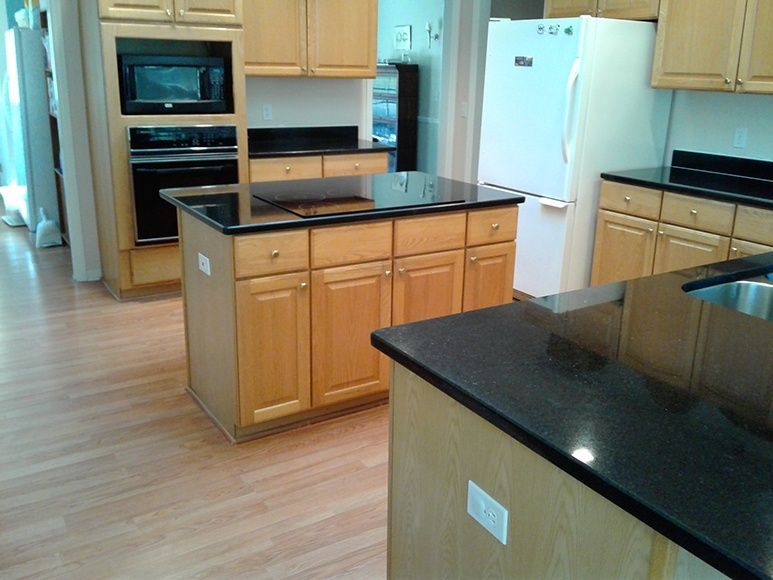 A kitchen with wooden cabinets and black counter tops
