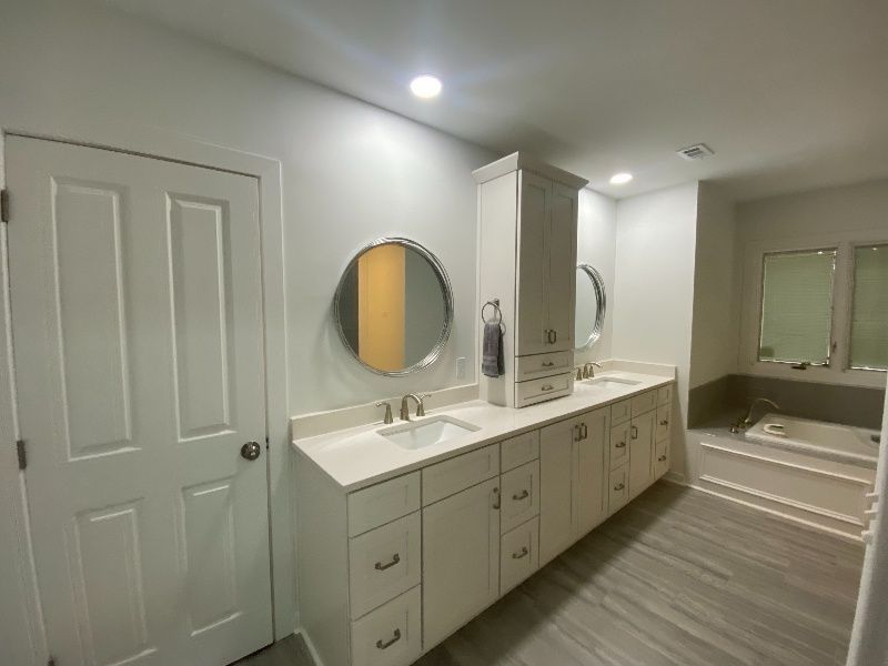 A bathroom with two sinks , two mirrors and a bathtub.