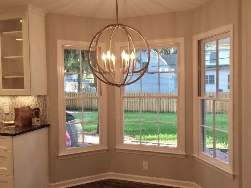 A kitchen with a chandelier hanging from the ceiling and a lot of windows.