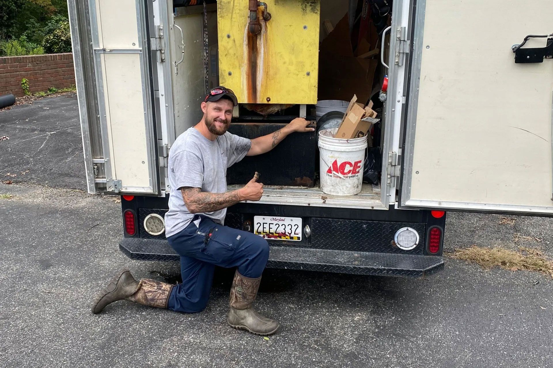 Man kneels beside a box truck, pointing at a yellow machine loaded in the back.