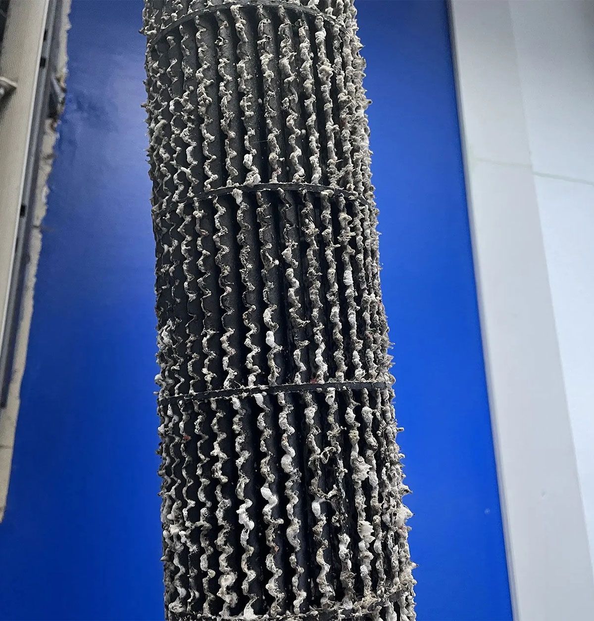 Close-up of a black corrugated filter panel against a blue background