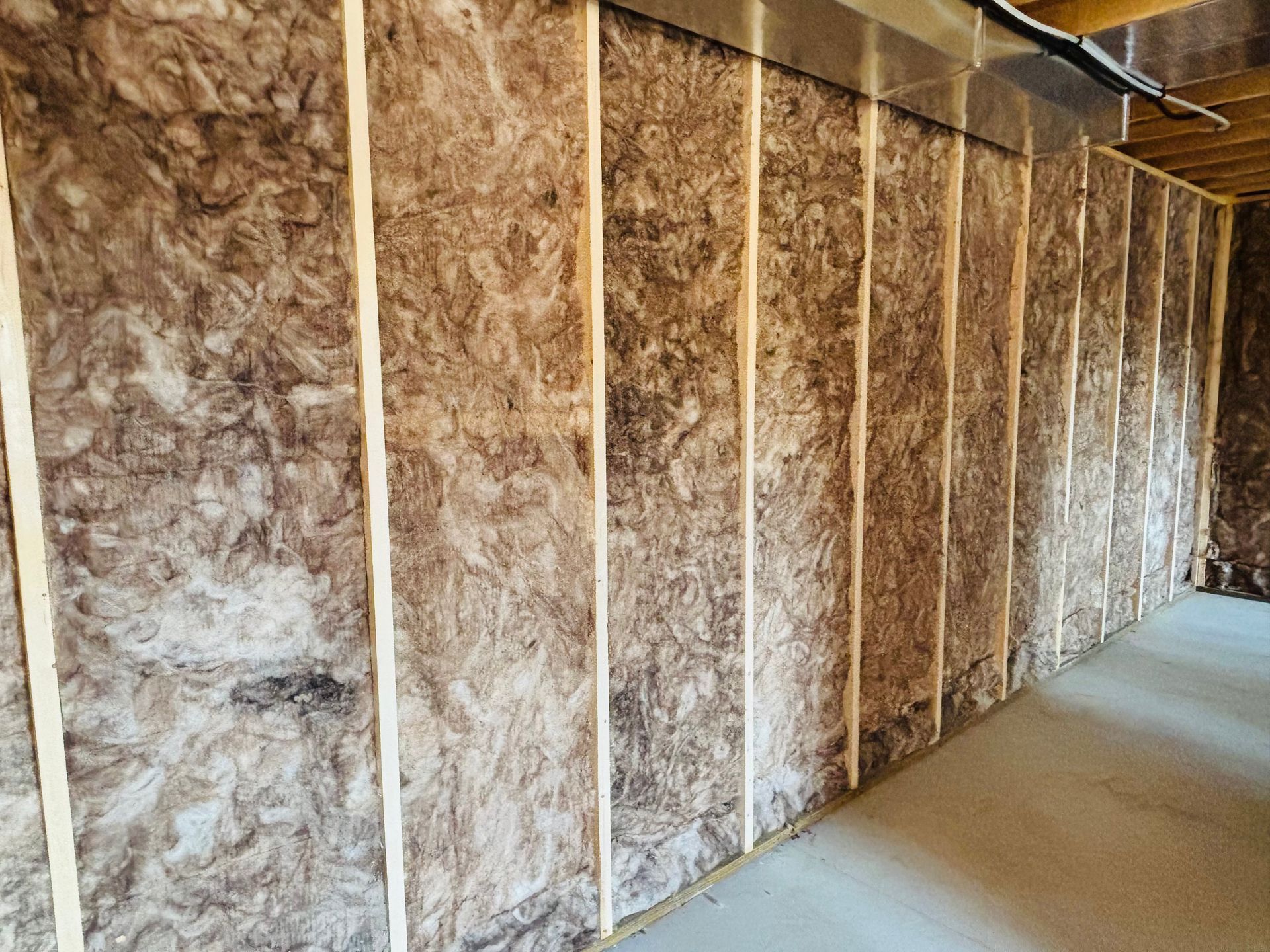 Interior wall with wood studs and brown insulation.