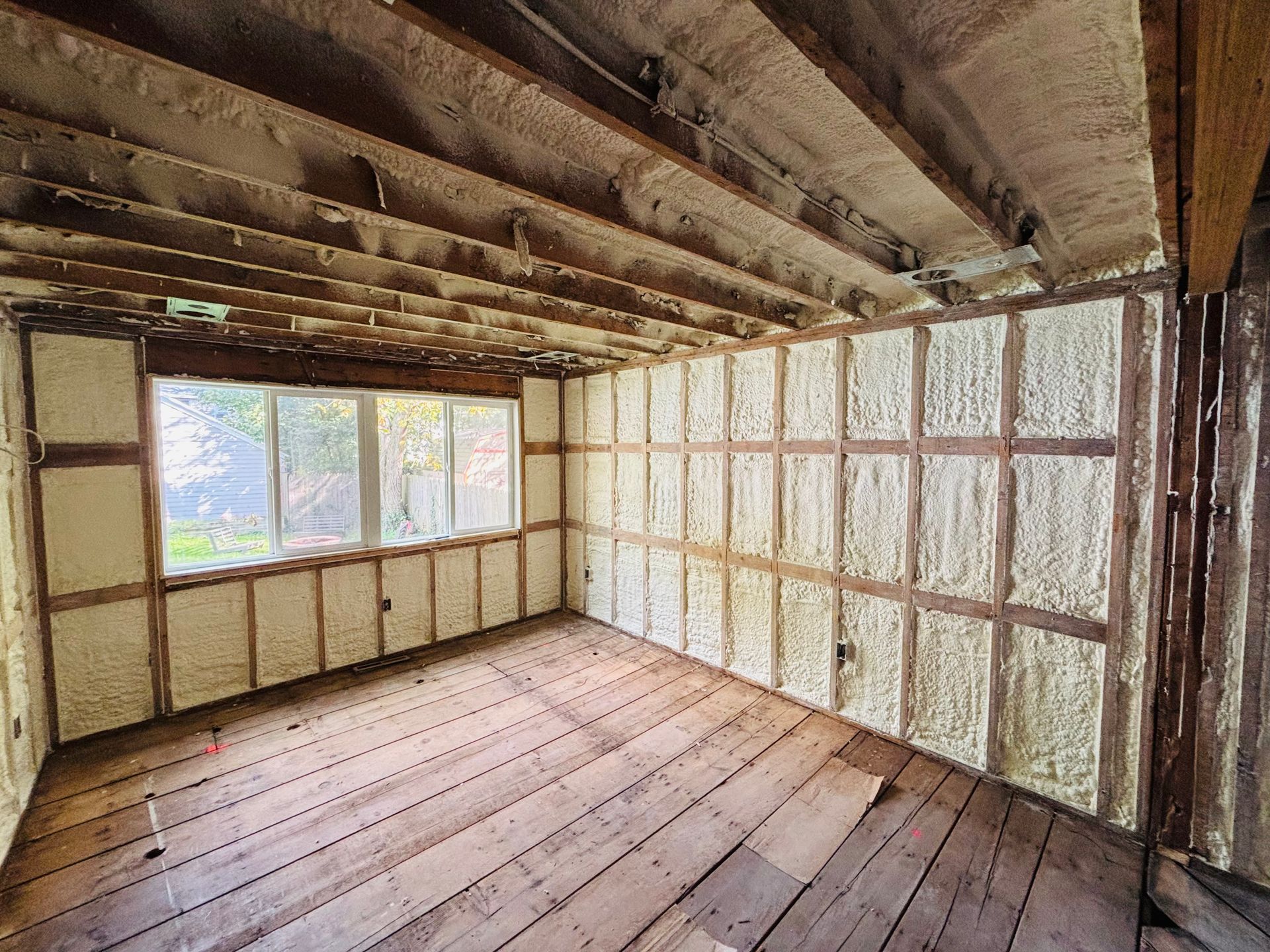 Interior room with exposed wood framing, insulated walls, and a window.