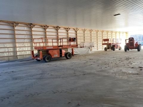 Inside of a building under construction, lift equipment along a wall.