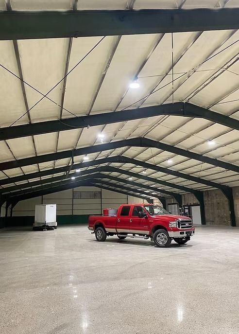 Red pickup truck parked inside a large warehouse with a high ceiling and bright lighting.