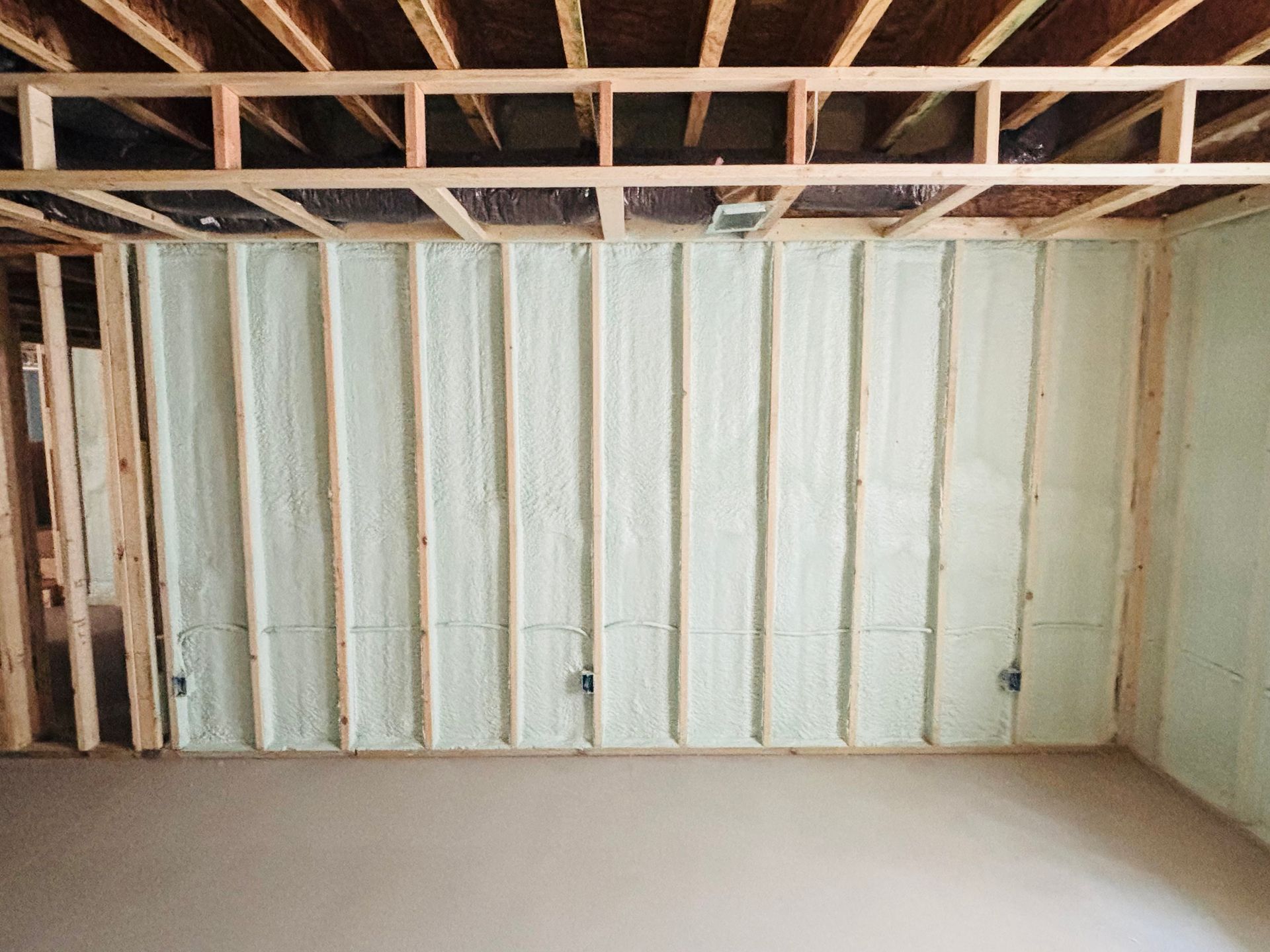 Interior wall studs with spray foam insulation, unfinished basement. Wooden frame.