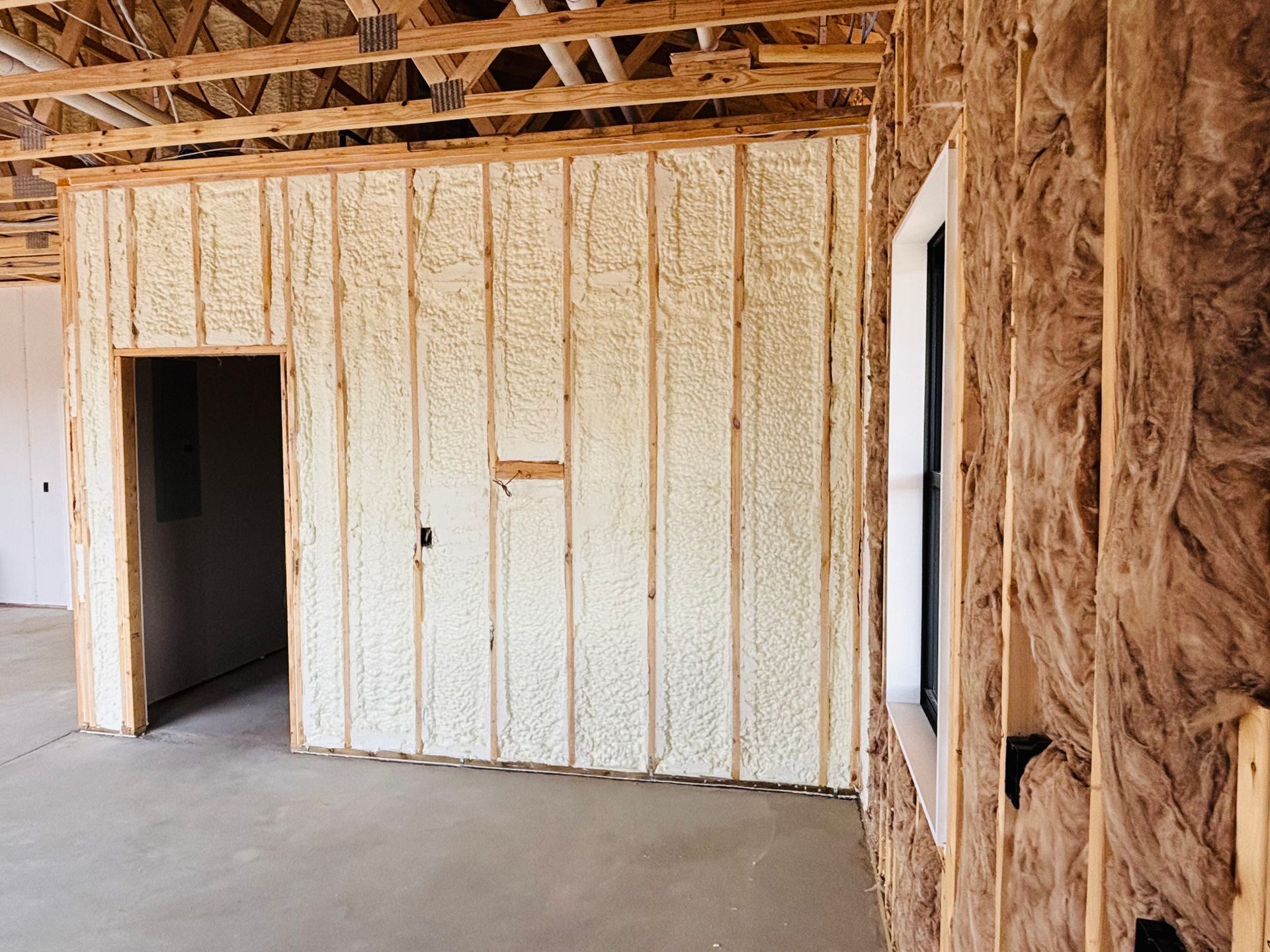Interior of a building under construction, walls insulated with light-colored foam.