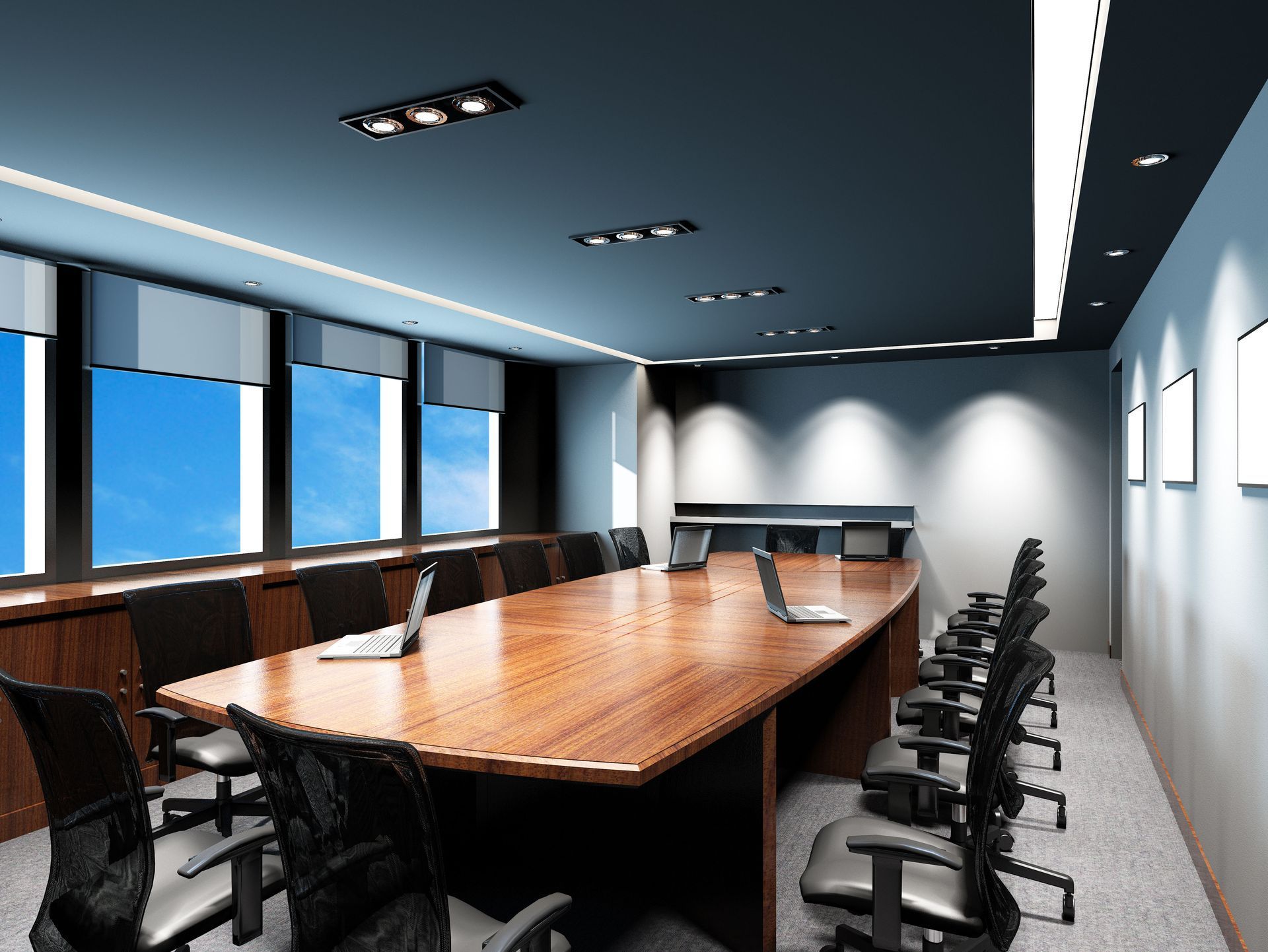 Modern conference room with long wooden table, black chairs, and large windows overlooking a blue sky.