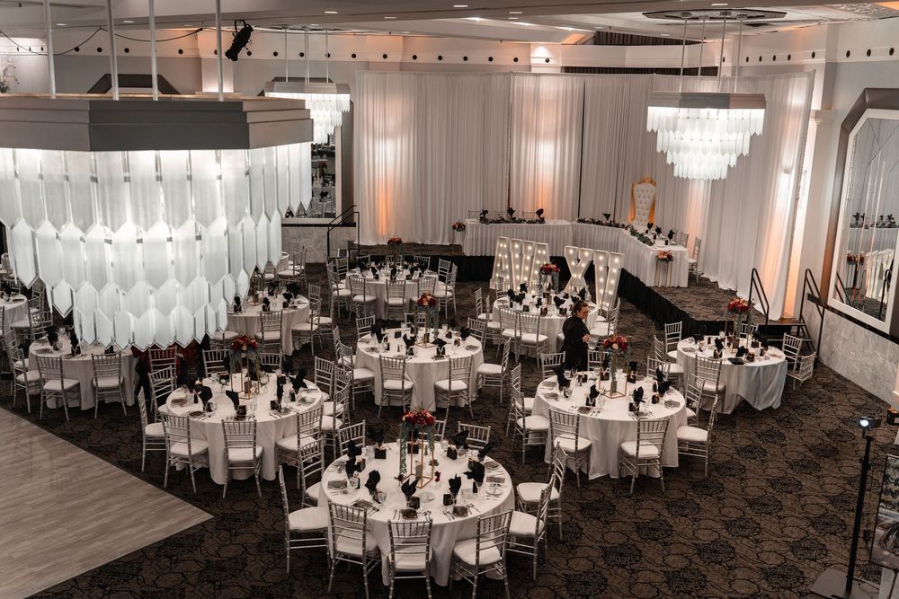 Elegant banquet hall with round tables, white chairs, and large windows overlooking a scenic outdoor view