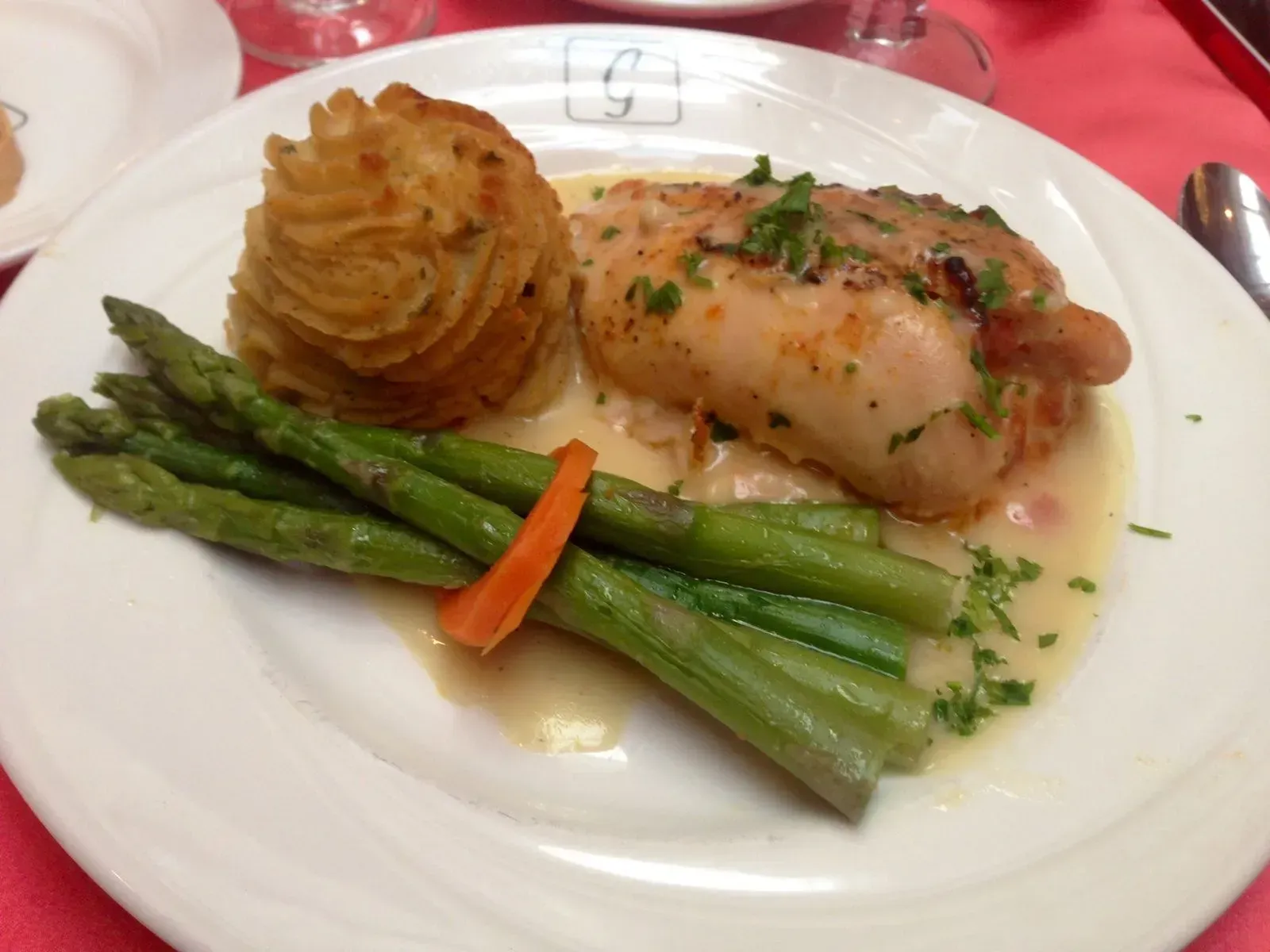Plated asparagus, mashed potatoes, and roasted fish on a white dinner plate