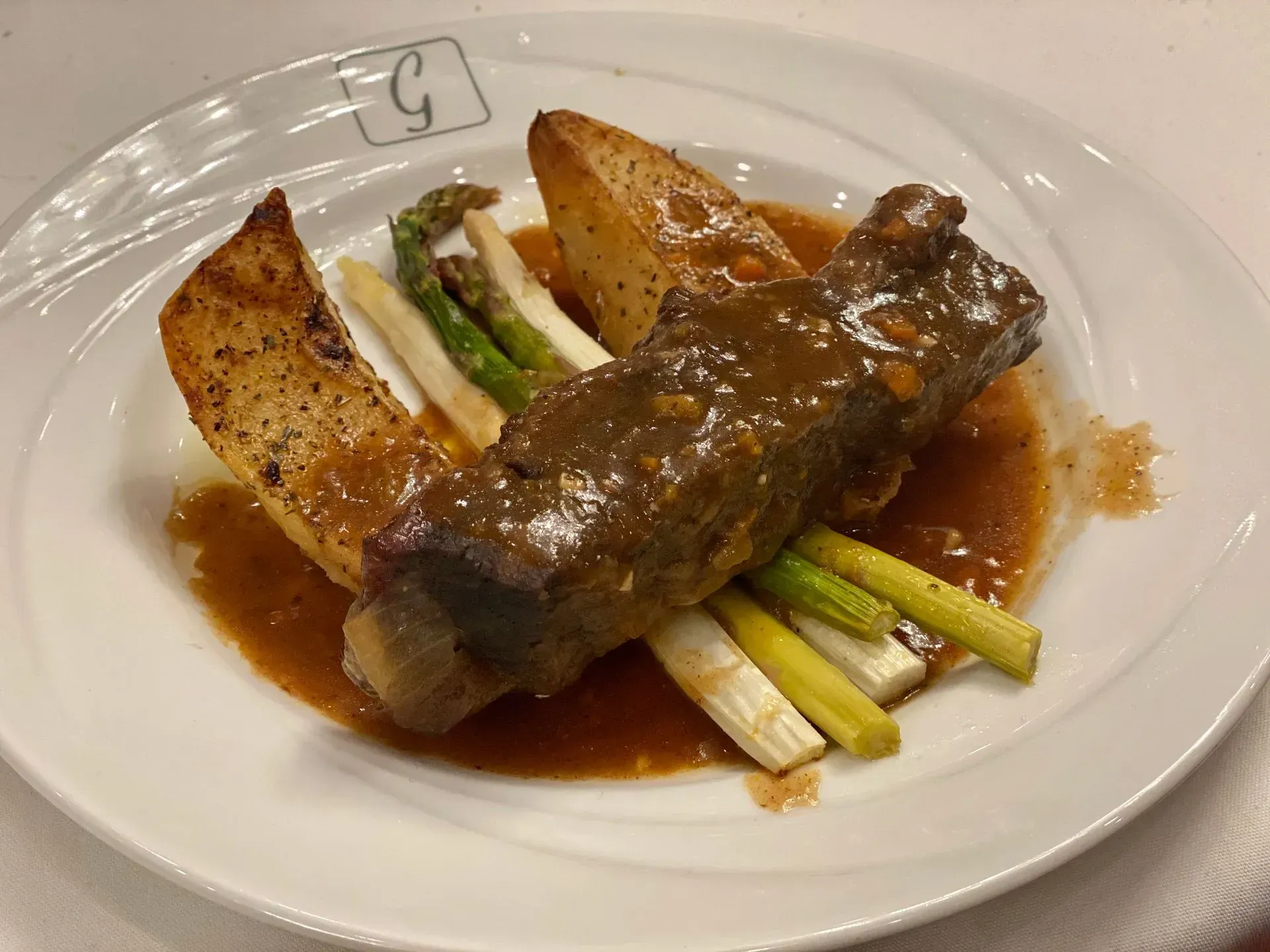 Plated saucy fish with asparagus and roasted potatoes on a white dish