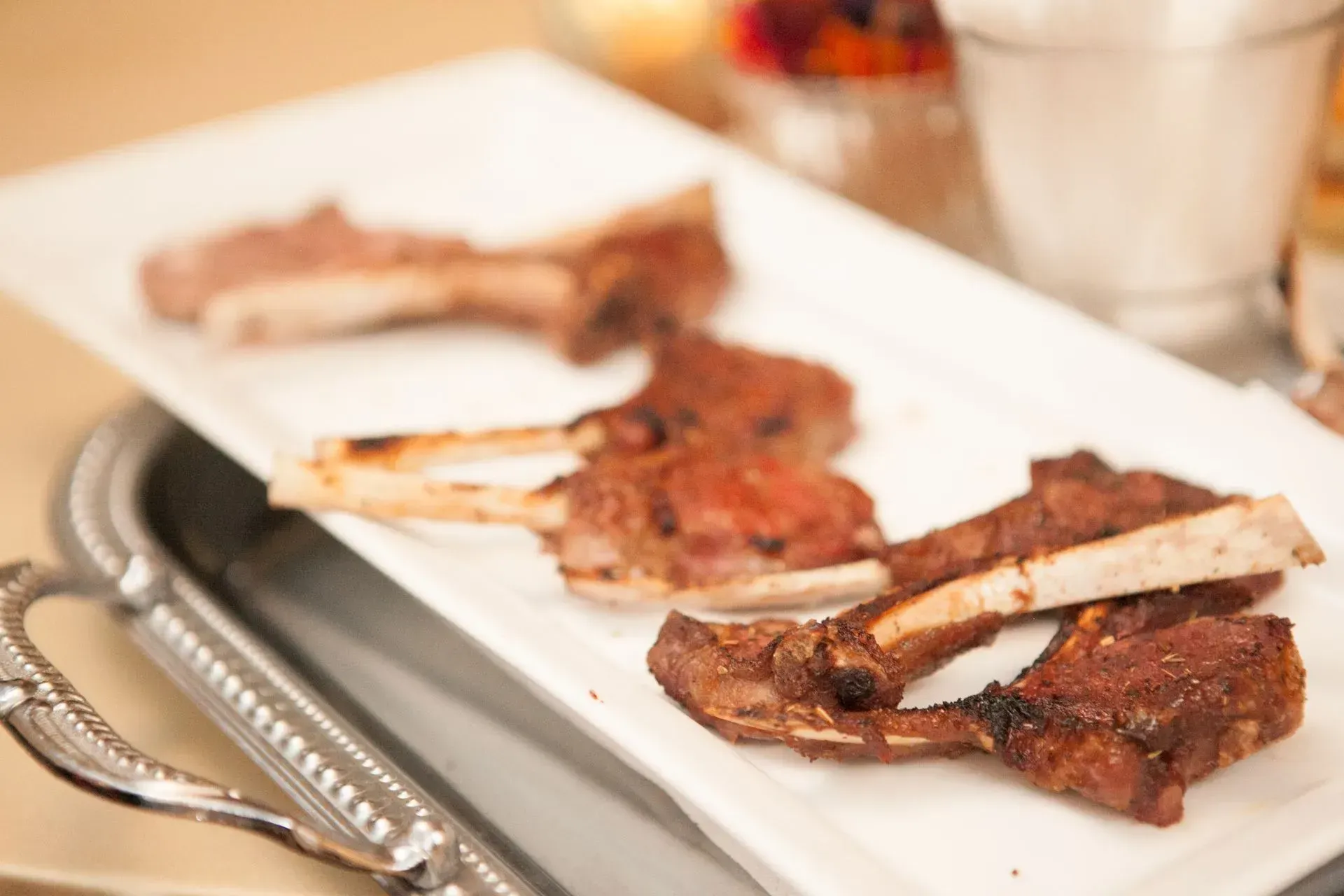 Grilled meat and ribs on a white platter at a dining table