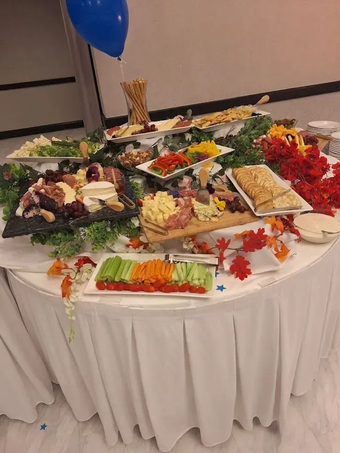 Buffet table with assorted salads, appetizers, and fruit on a white tablecloth in a banquet hall
