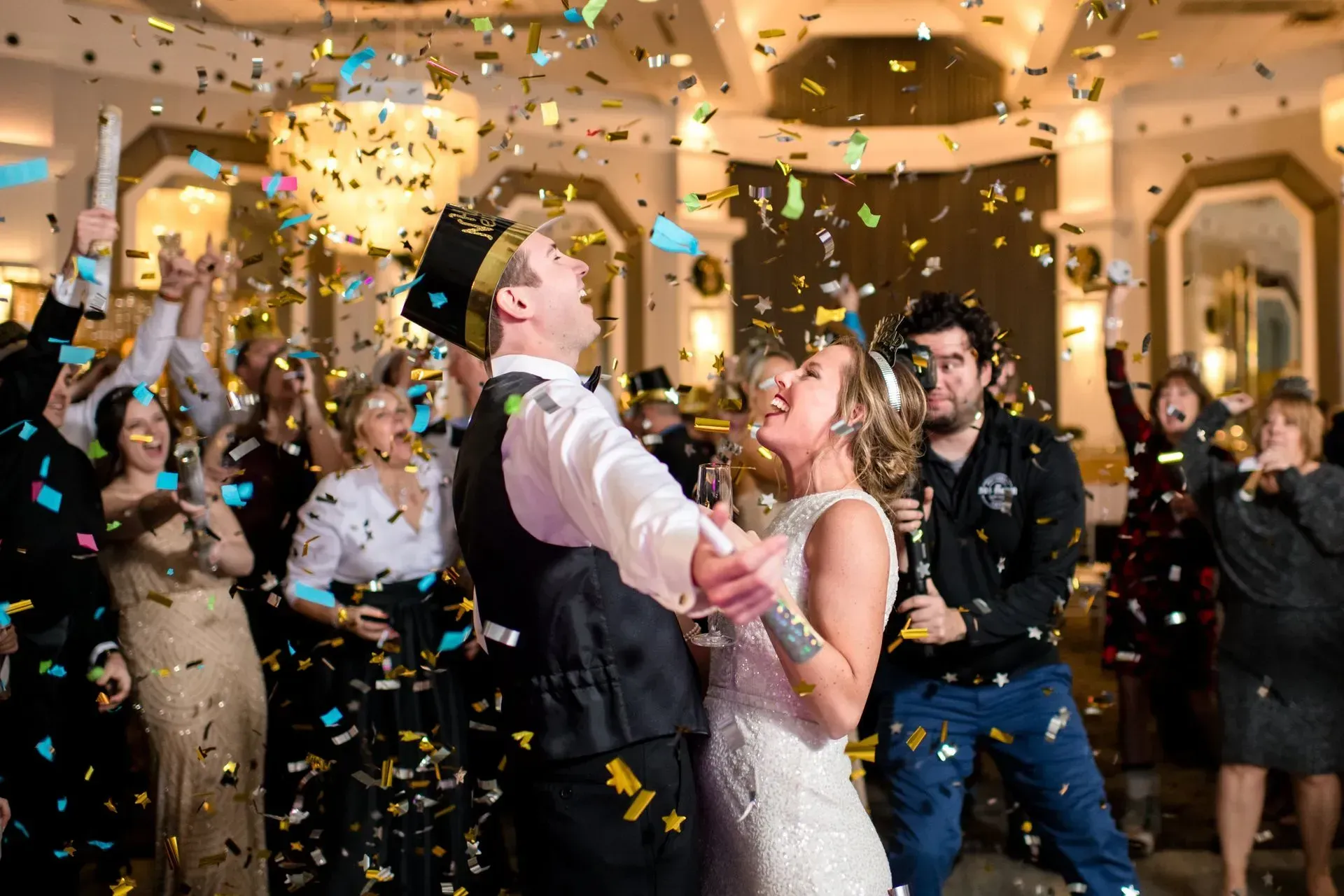 Wedding couple dancing amid falling confetti at a lively indoor celebration