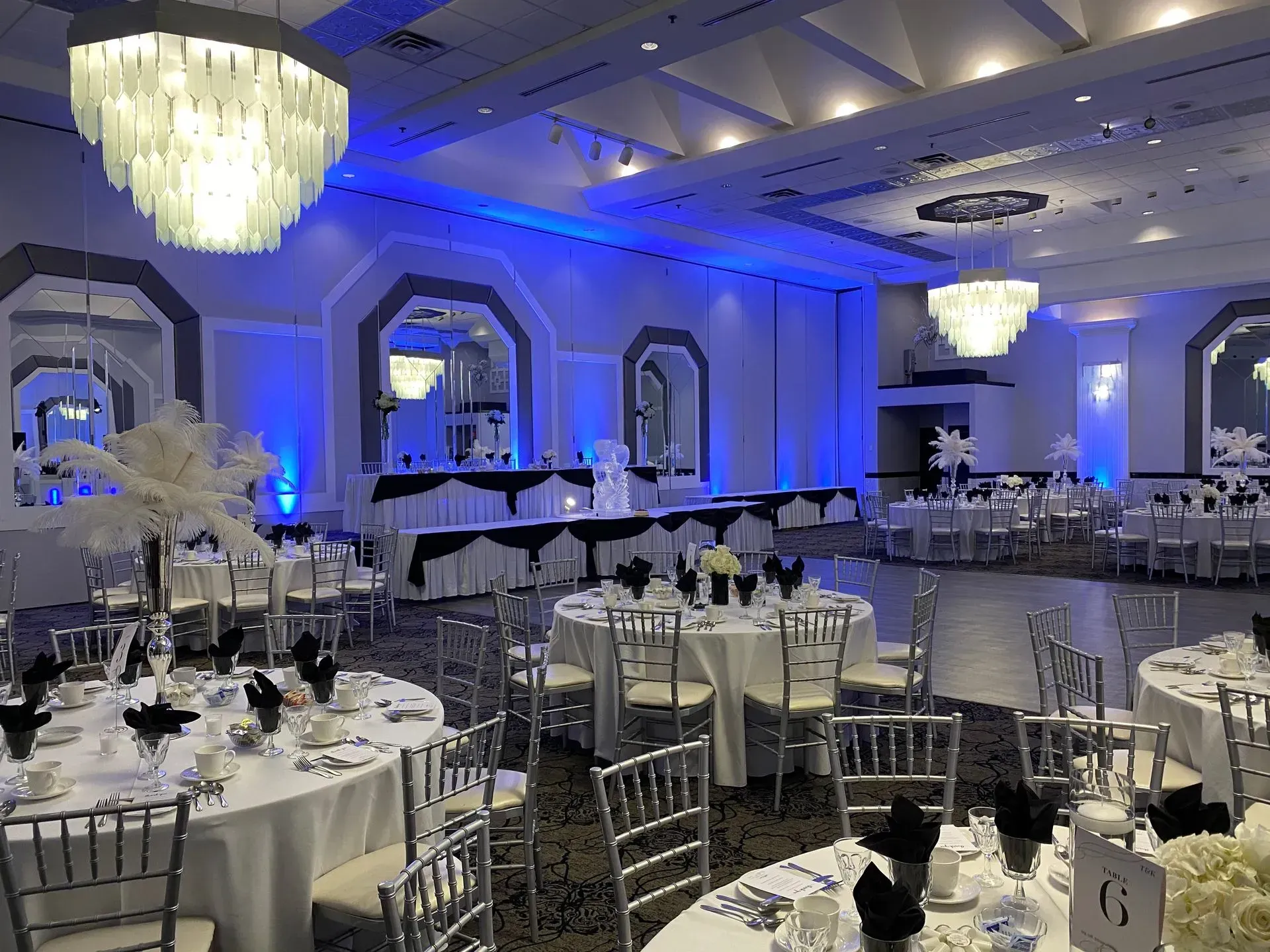 Elegant banquet hall with round tables, white chairs, and blue accent lighting before an event