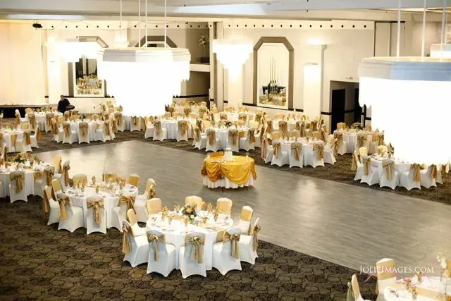 Elegant banquet hall with round tables draped in white and gold table settings, ready for an event