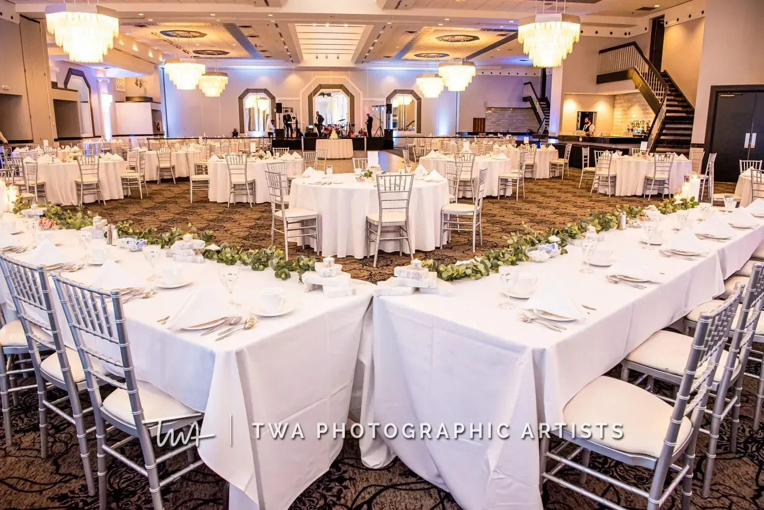 Elegant banquet hall with round white-clothed tables and silver chairs set for a formal event