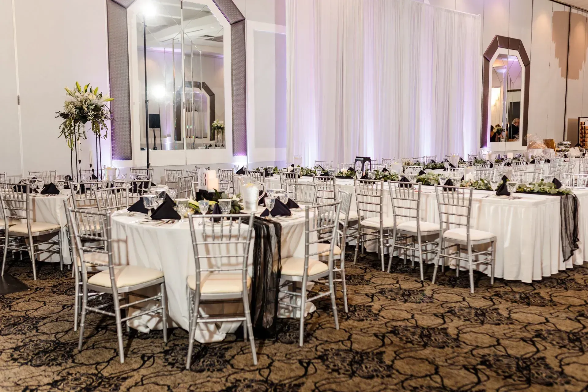 Elegant banquet hall with round tables, white chairs, and soft lighting set for an event