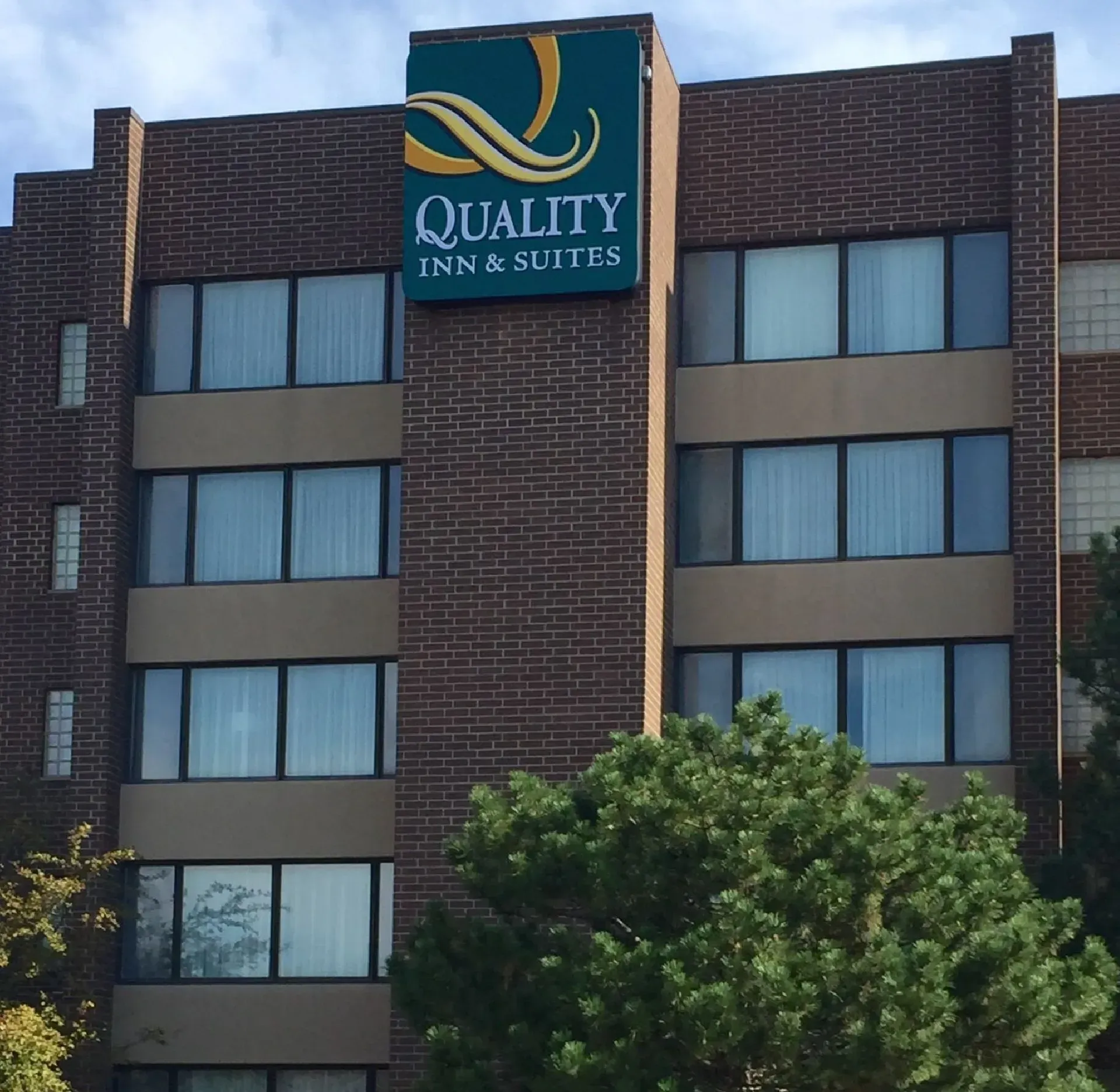 Quality Inn & Suites hotel exterior with brick facade and green sign