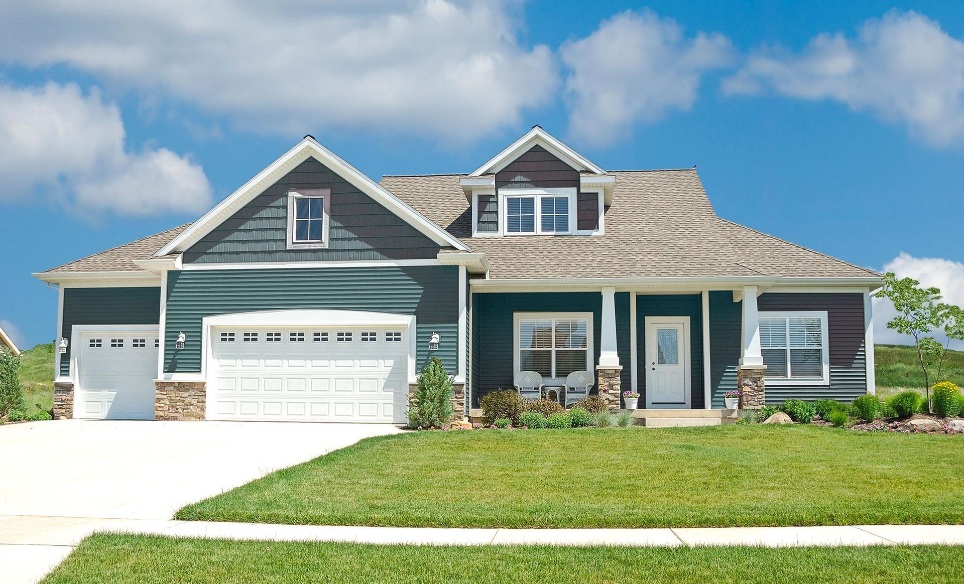 a large house with a green siding and a white garage door