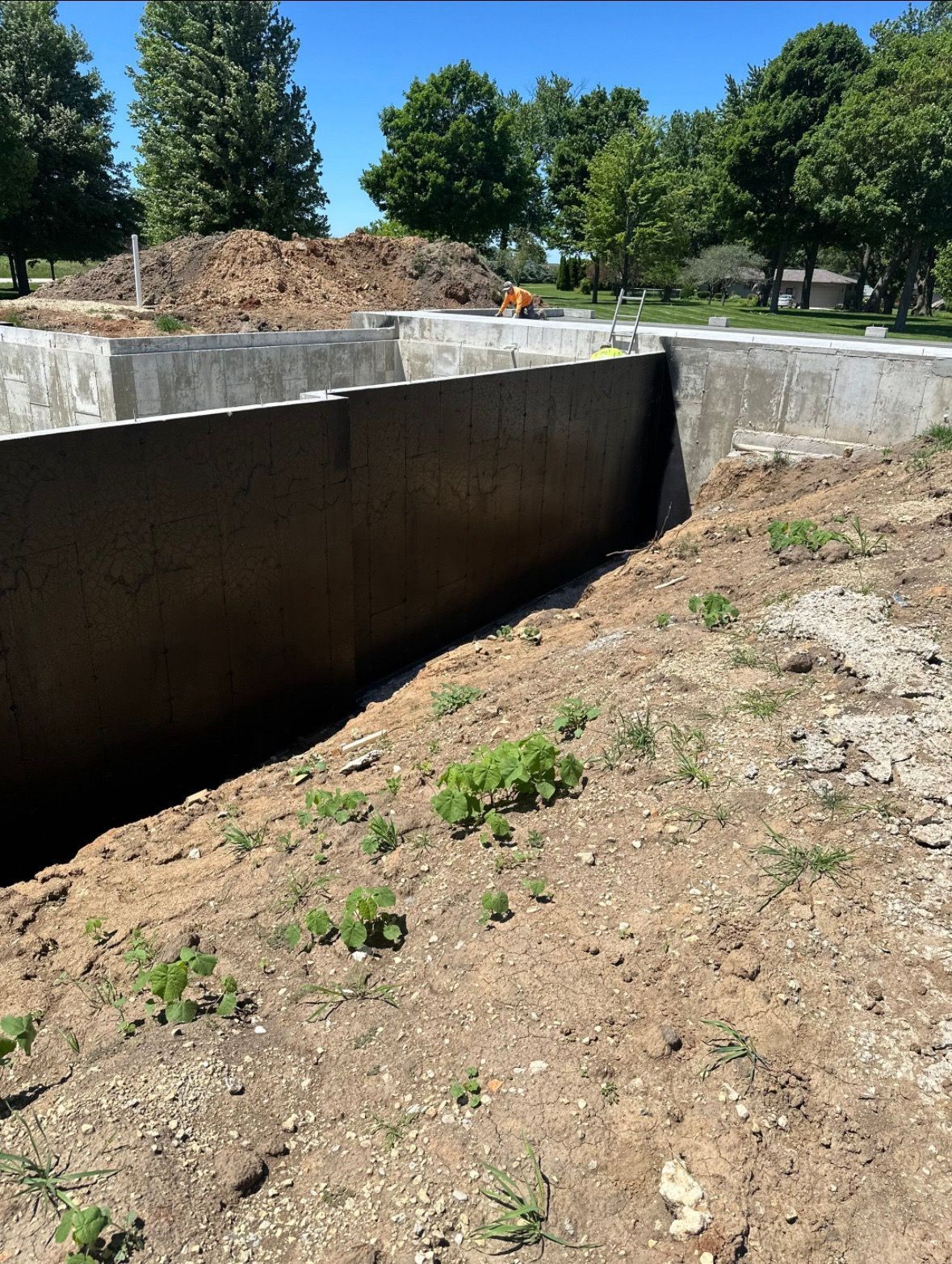 A large concrete wall is surrounded by dirt and trees.