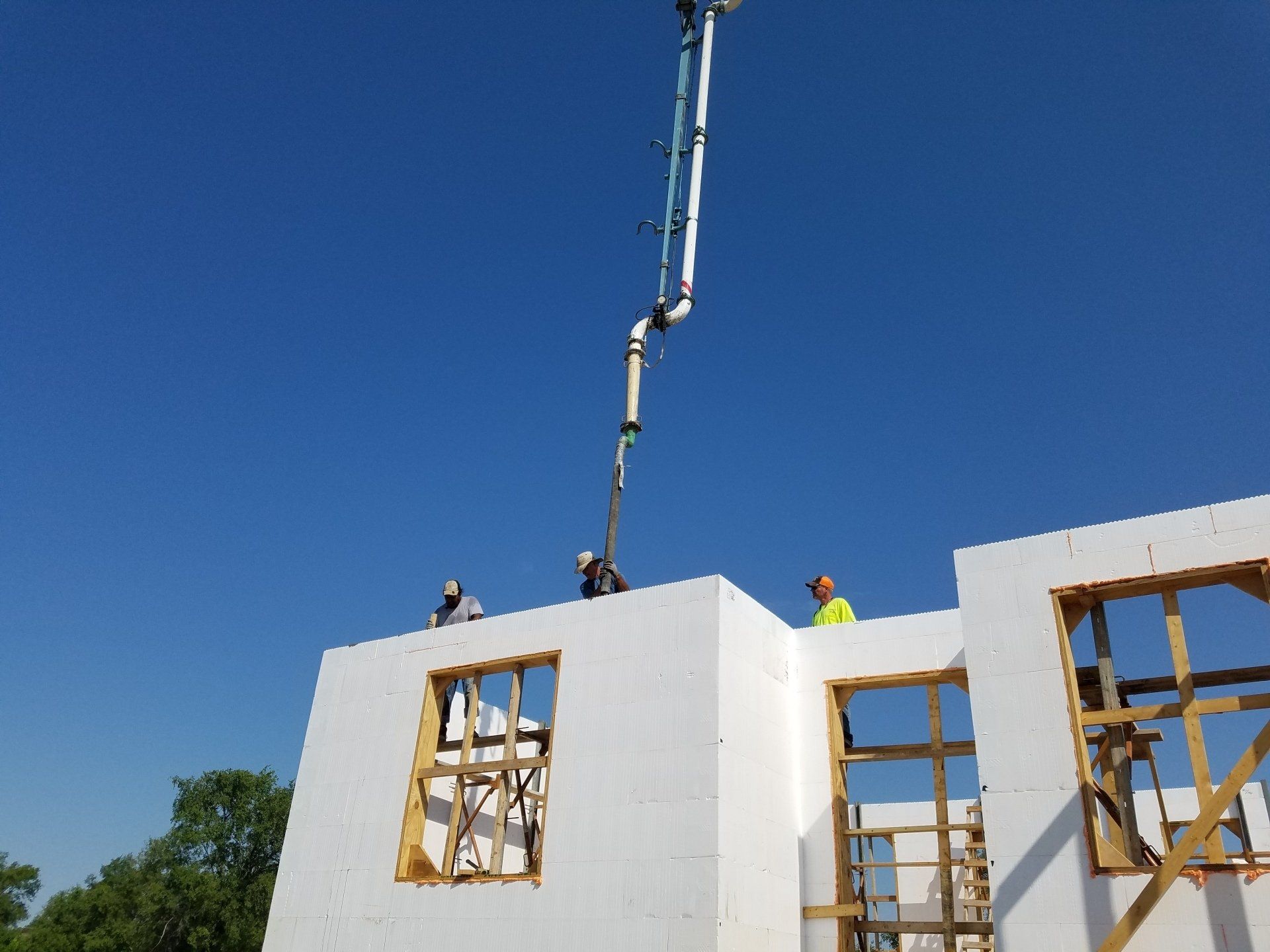 A concrete pump is being used to pour concrete into a building under construction.