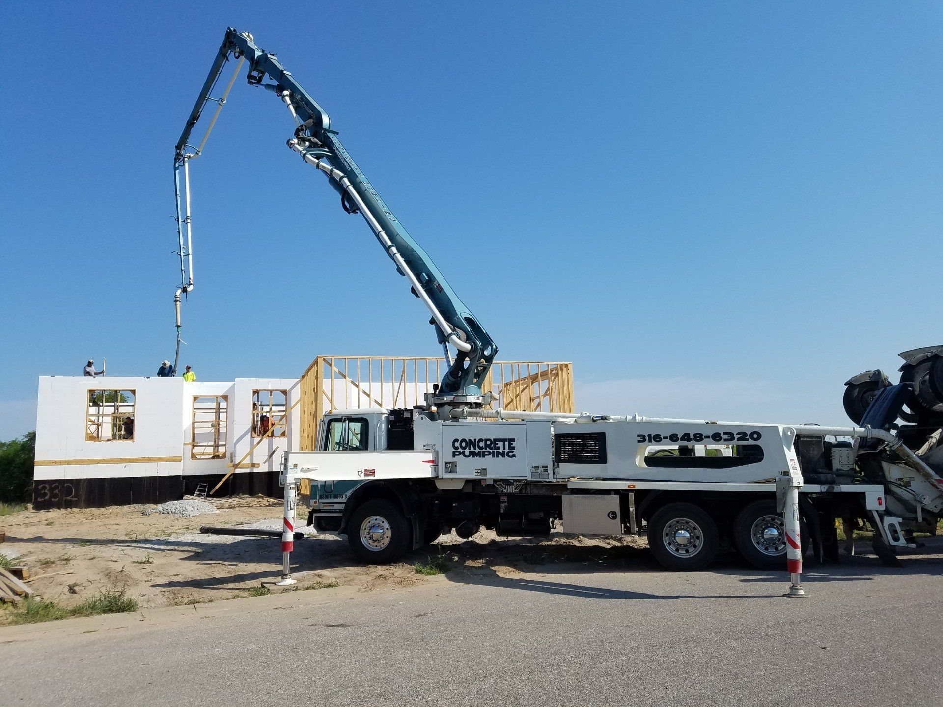 A concrete pump truck is pumping concrete into a house under construction.