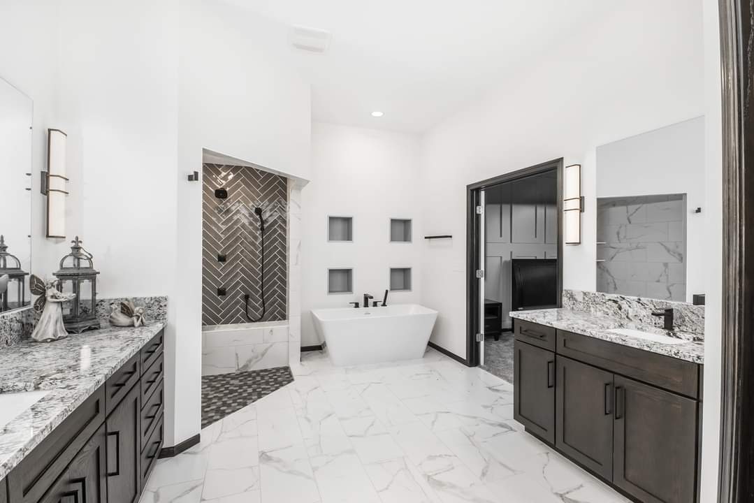 A bathroom with two sinks , a tub , and a walk in shower.