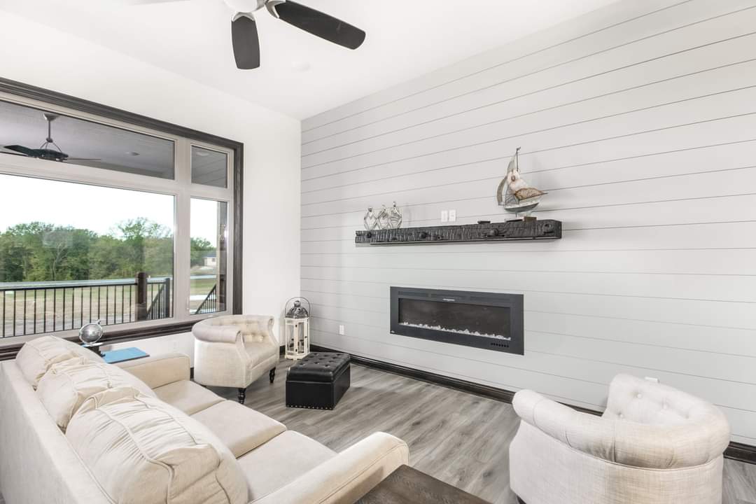 A living room with a couch , chair , fireplace and ceiling fan.