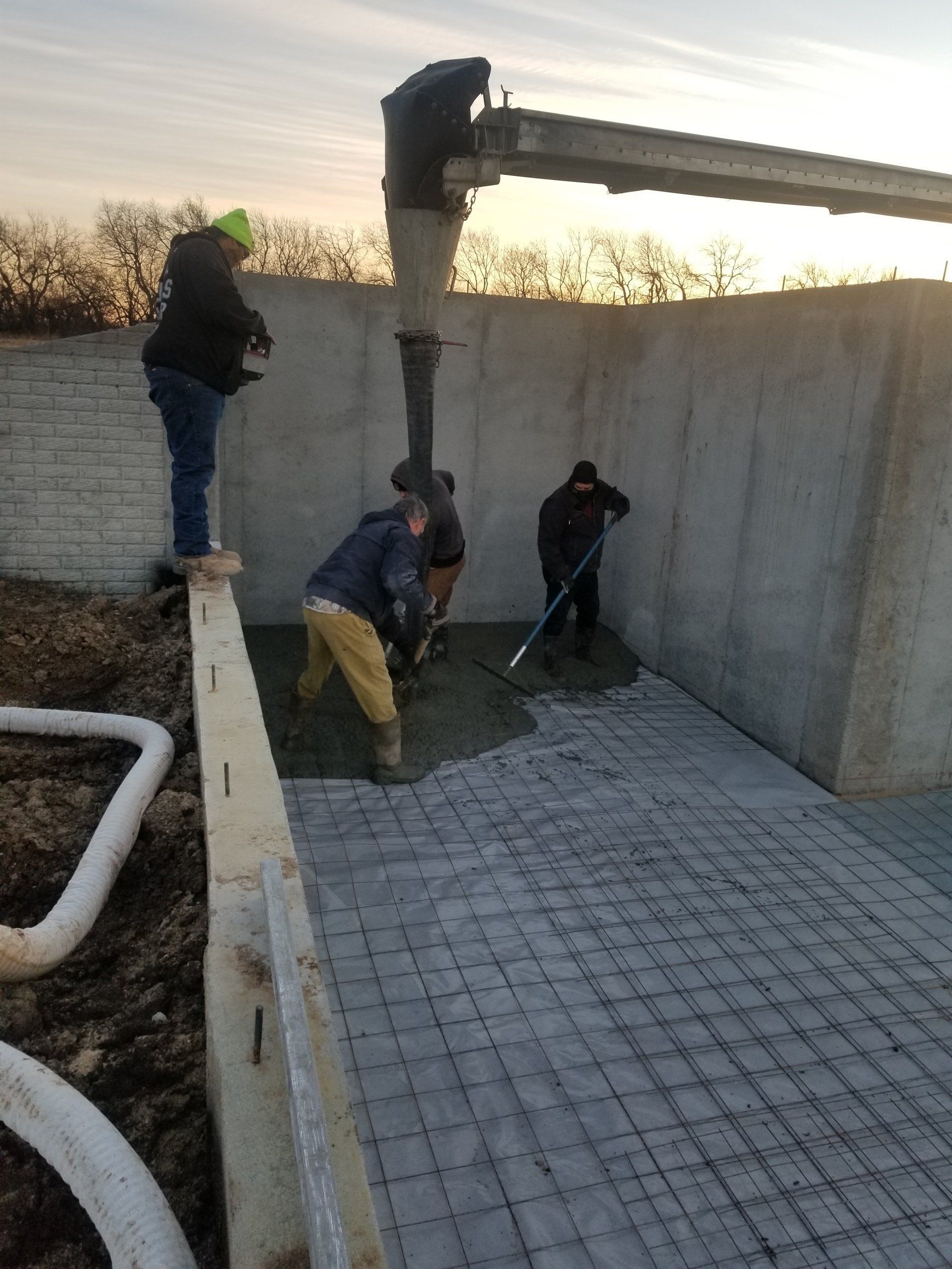A group of men are working on a concrete driveway.