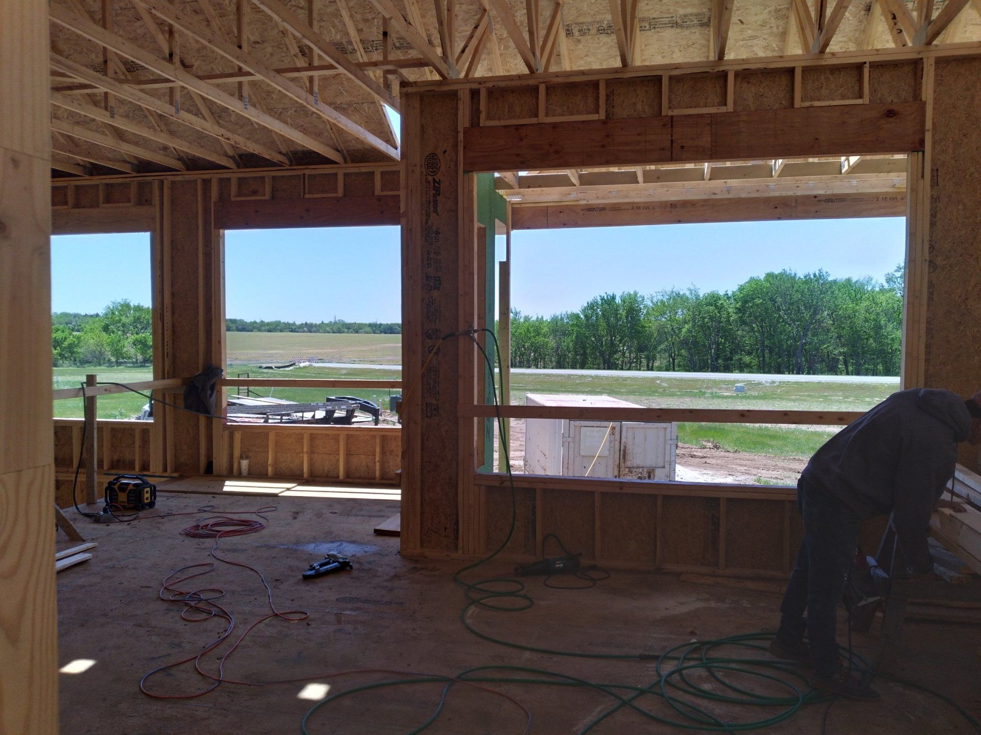 A man is working on a window in a house under construction.