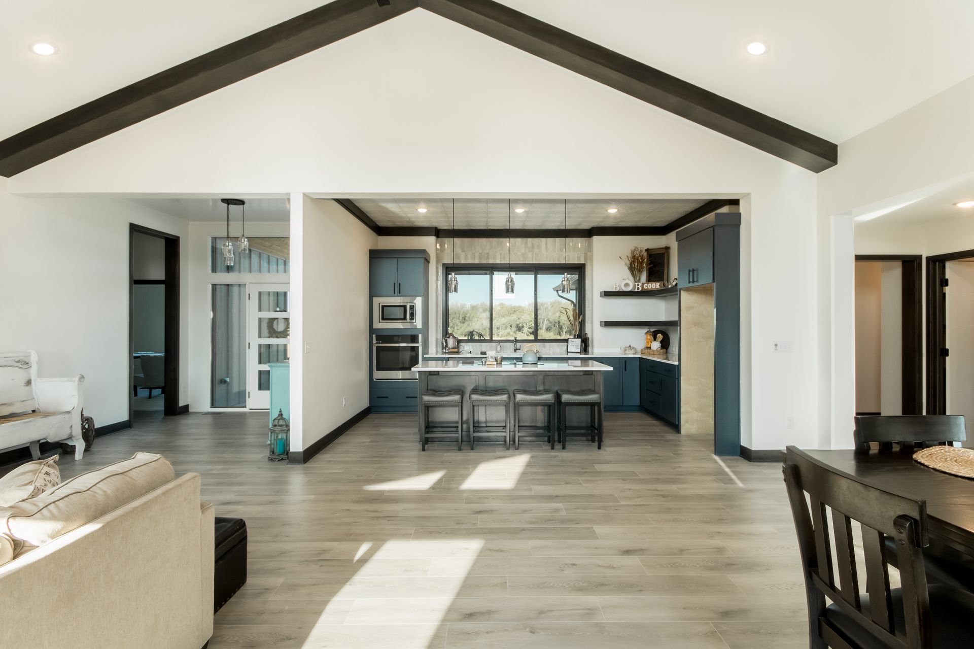 A living room filled with furniture and a kitchen with a vaulted ceiling.