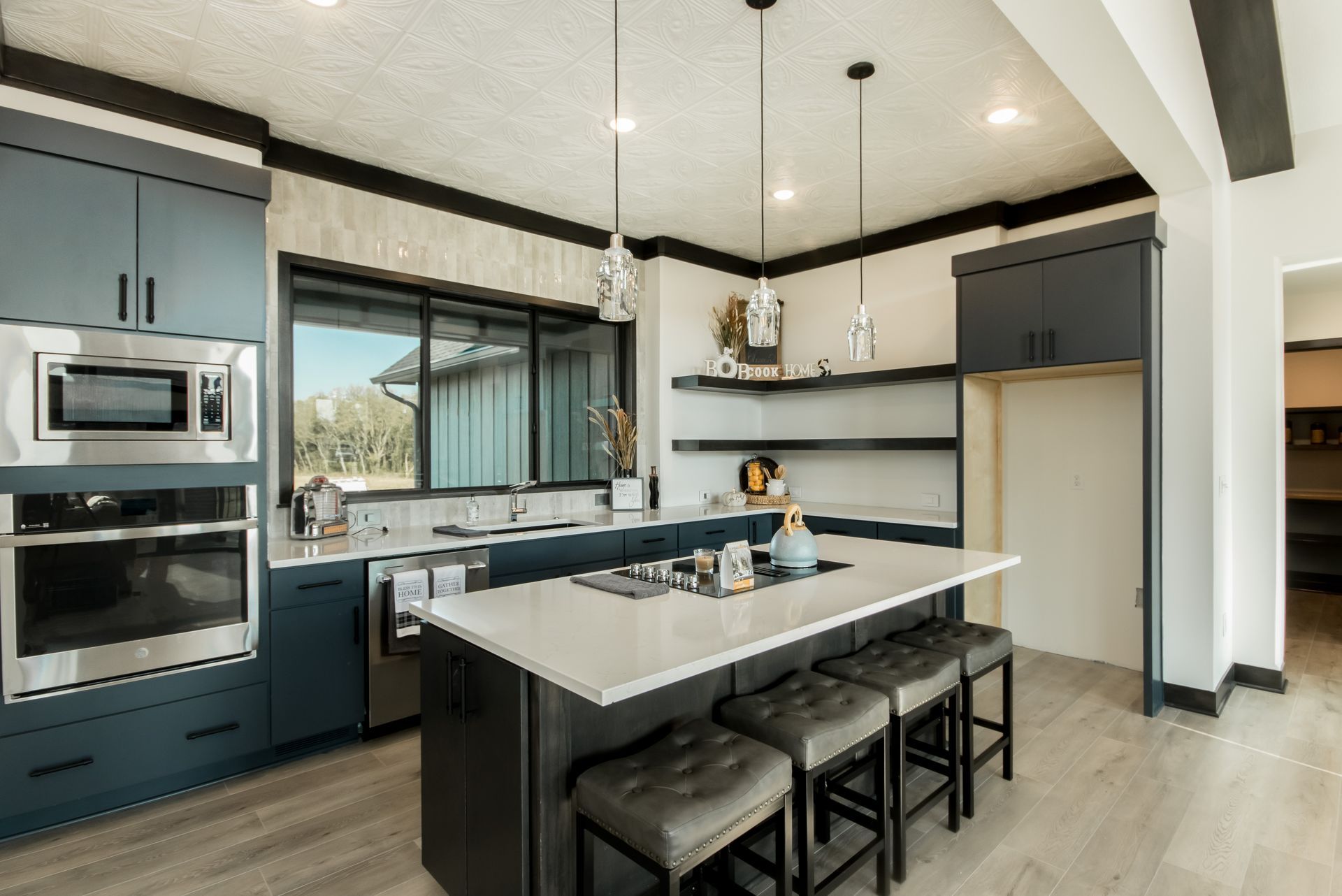 A kitchen with blue cabinets , white counter tops , stainless steel appliances and a large island.