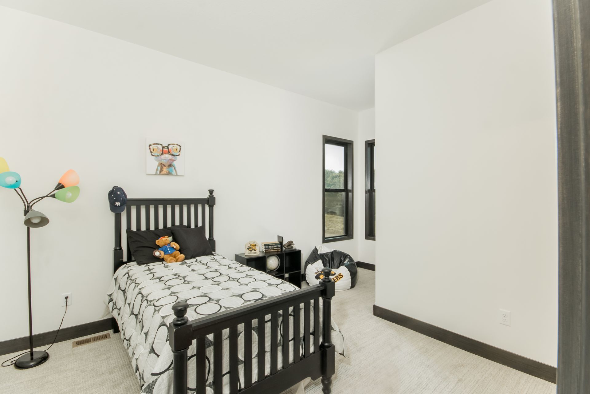 A bedroom with a black bed and a lamp.