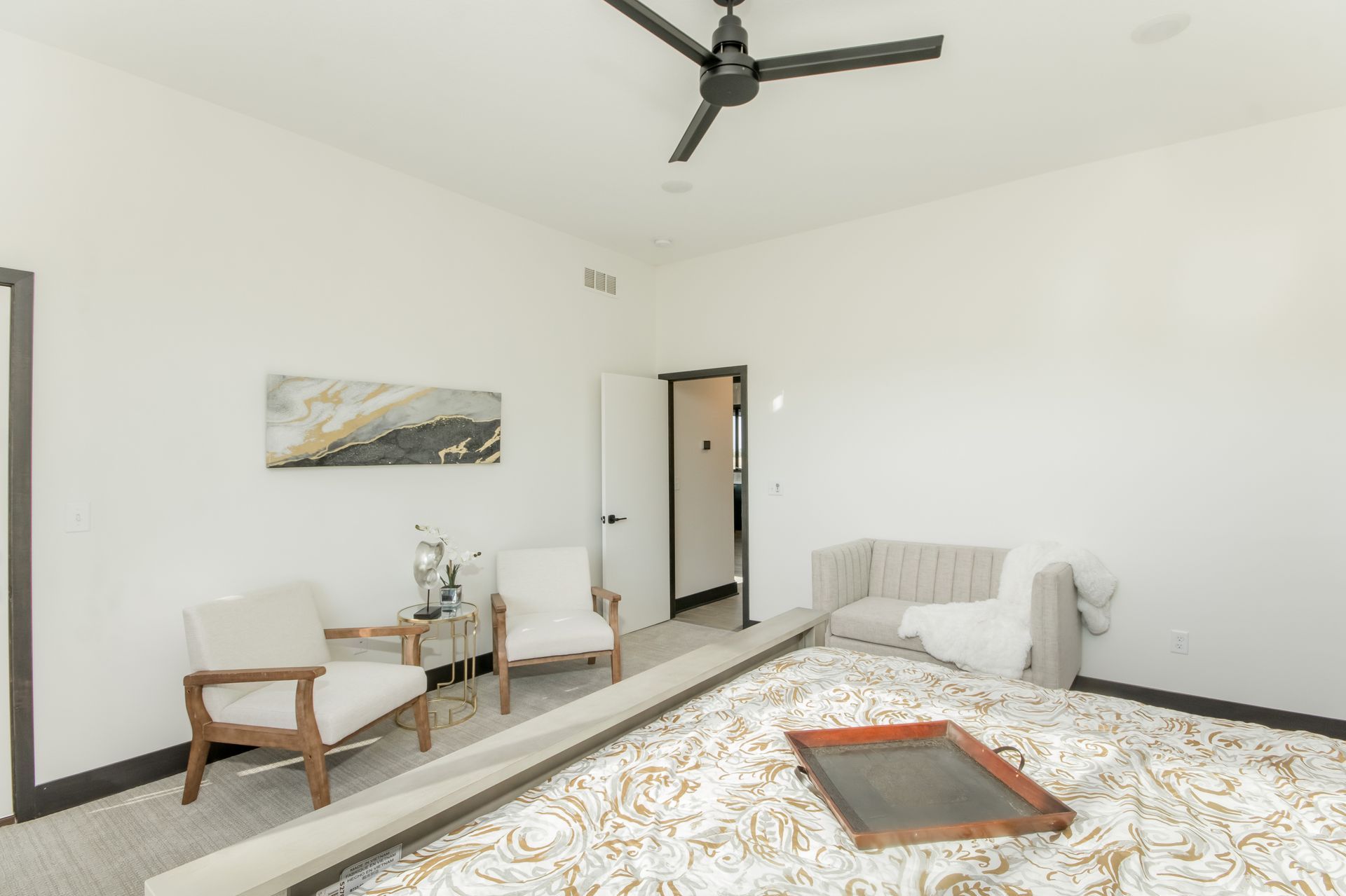 A bedroom with a bed , chairs , and a ceiling fan.