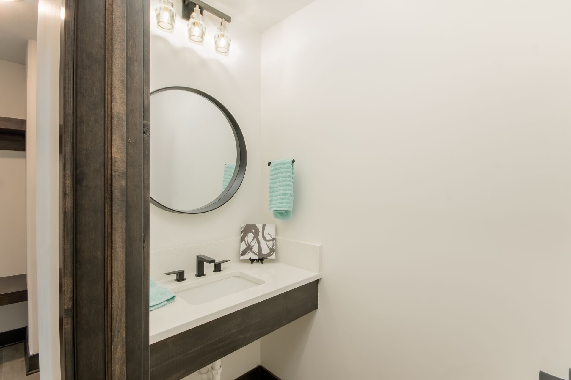 A bathroom with a sink , mirror and towel rack.