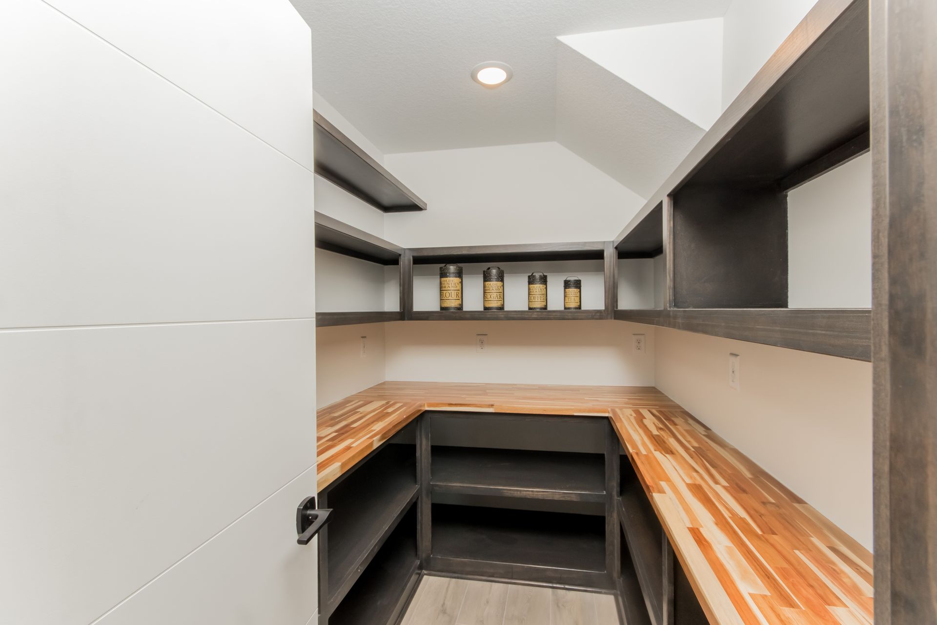 A walk in pantry with wooden shelves and a white door.