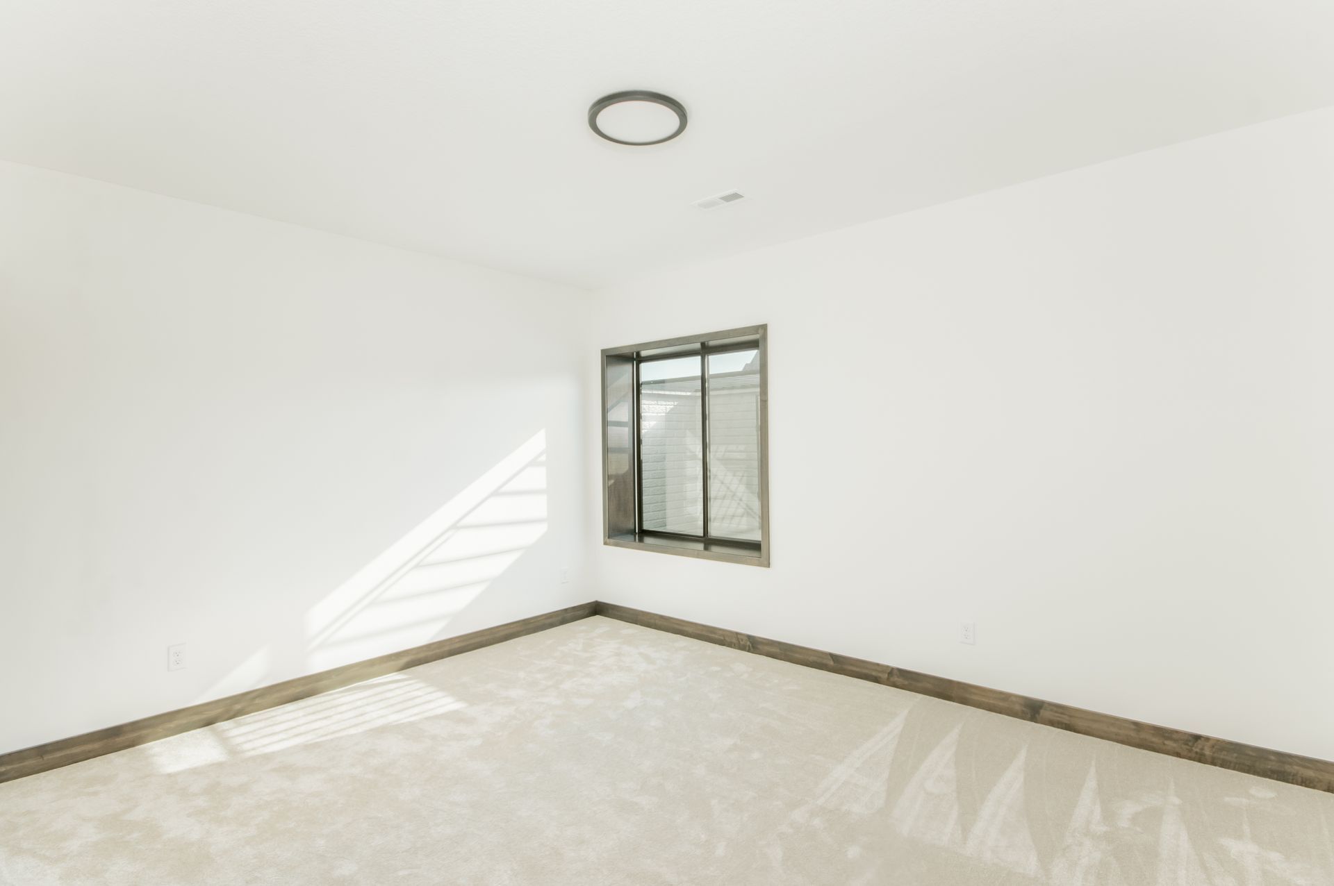 An empty room with a window and a ceiling light.
