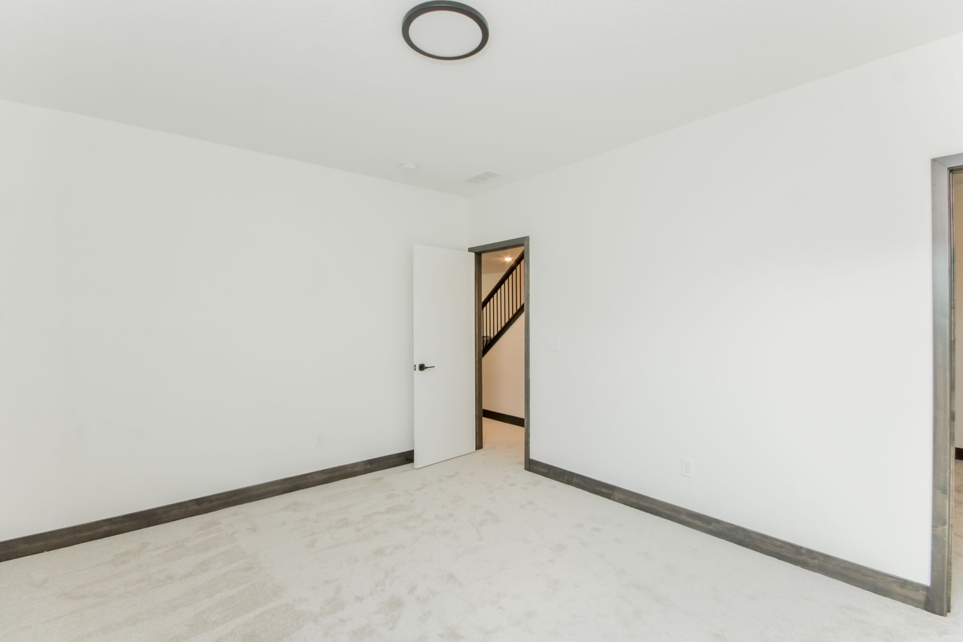 An empty room with white walls and a door leading to a walk in closet.