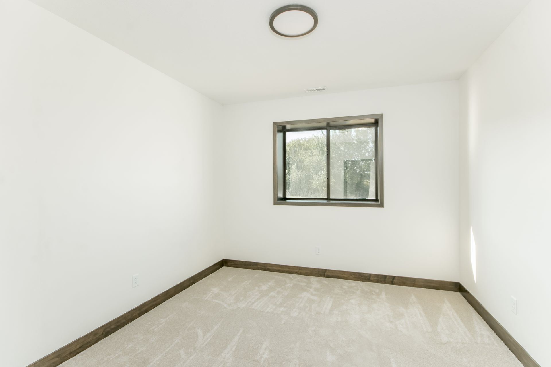 An empty room with a window and a ceiling light