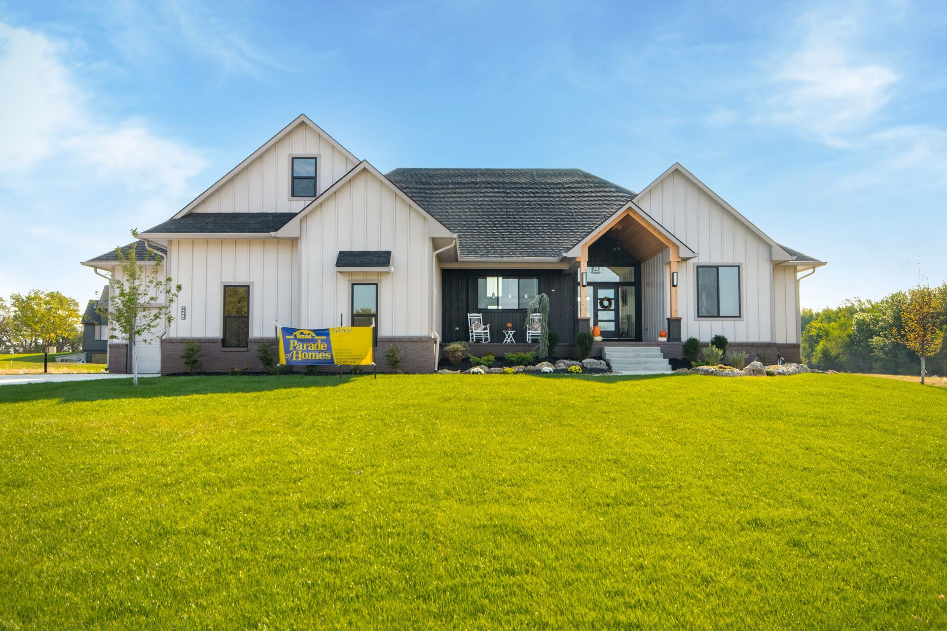 A large white house is sitting on top of a lush green field.