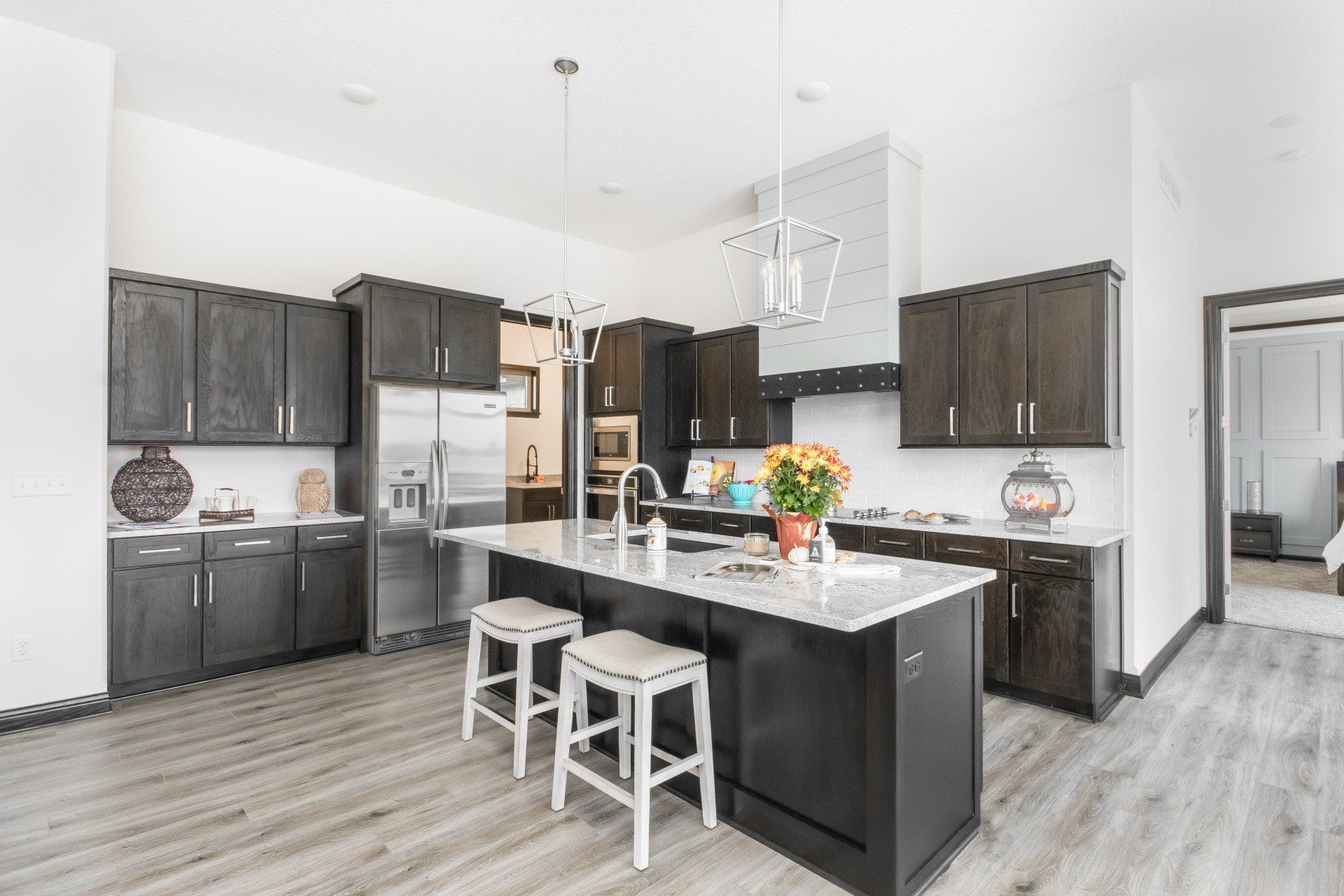 A kitchen with a large island , stools and a refrigerator.