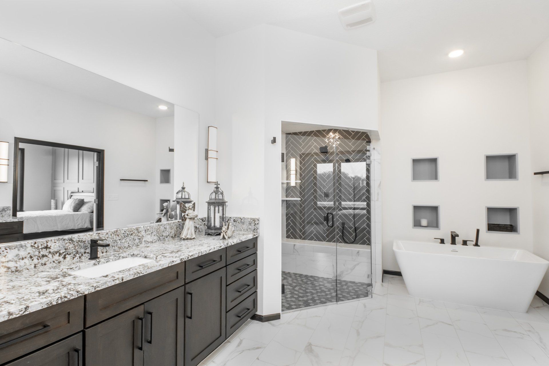 A bathroom with two sinks , a tub and a mirror.