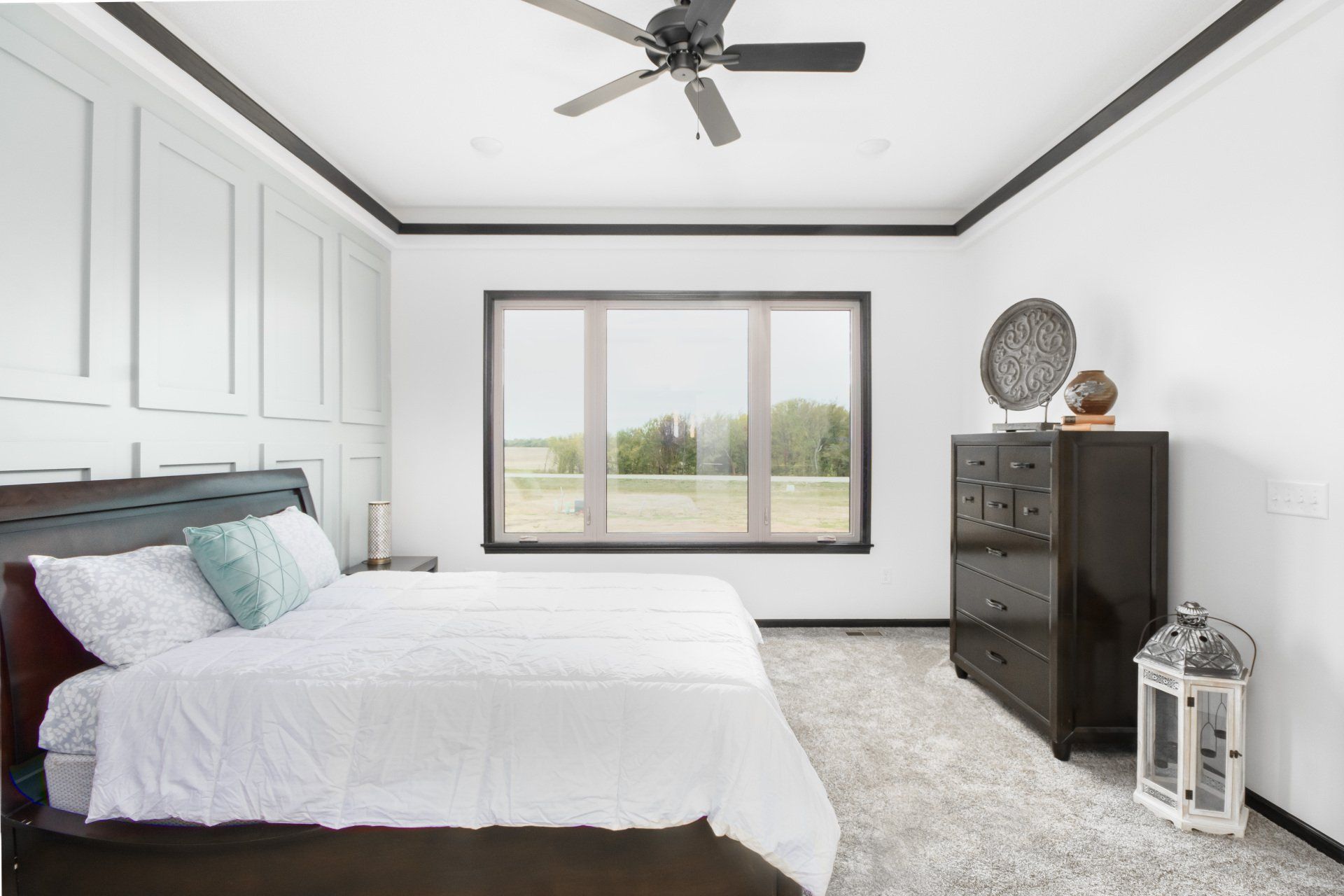 A bedroom with a bed , dresser , and ceiling fan.