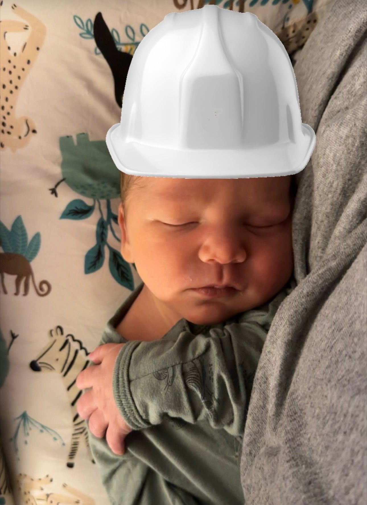 Sleeping baby wearing a white construction helmet.